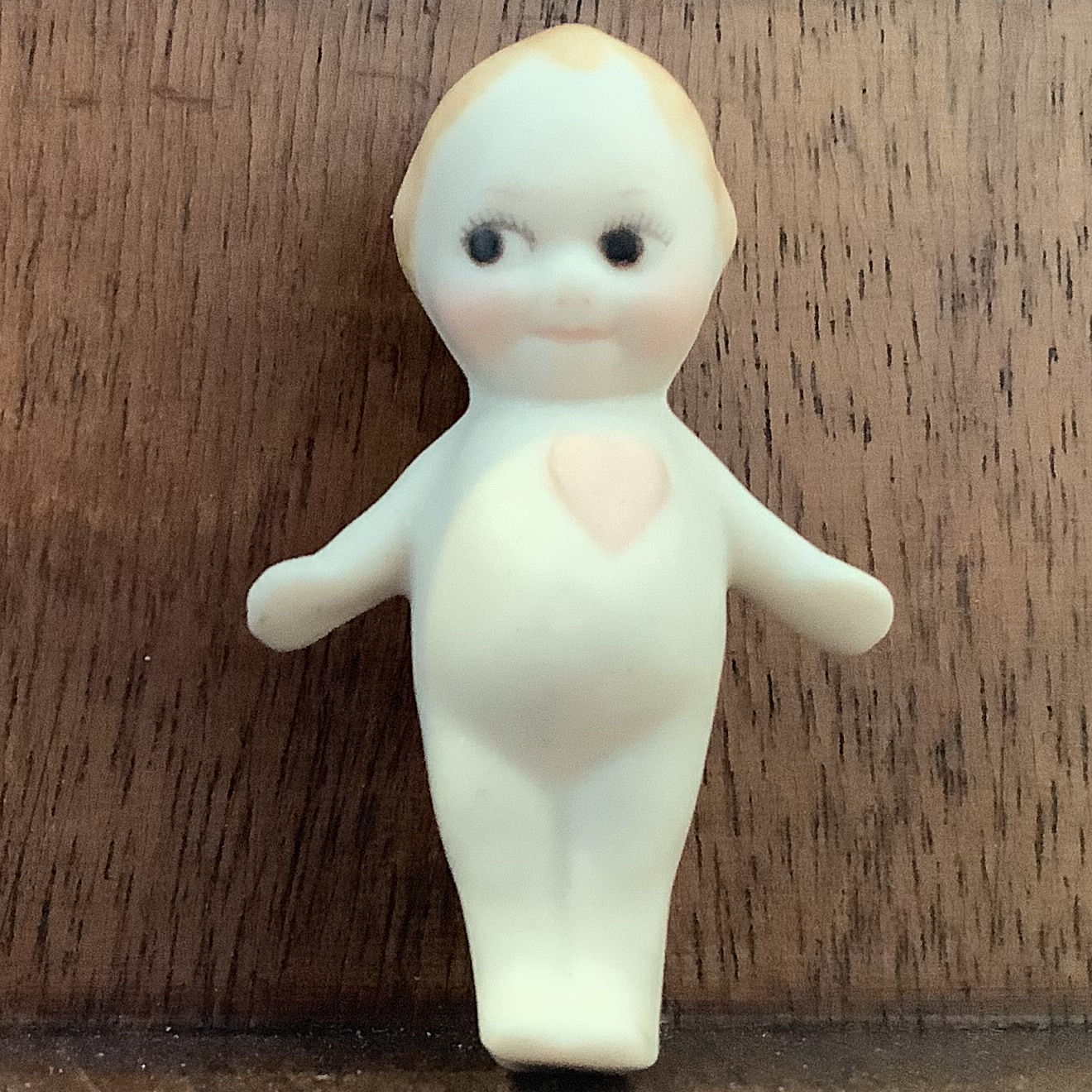 Kewpie doll brooch; naked baby with heart printed on chest and pointed blond hair