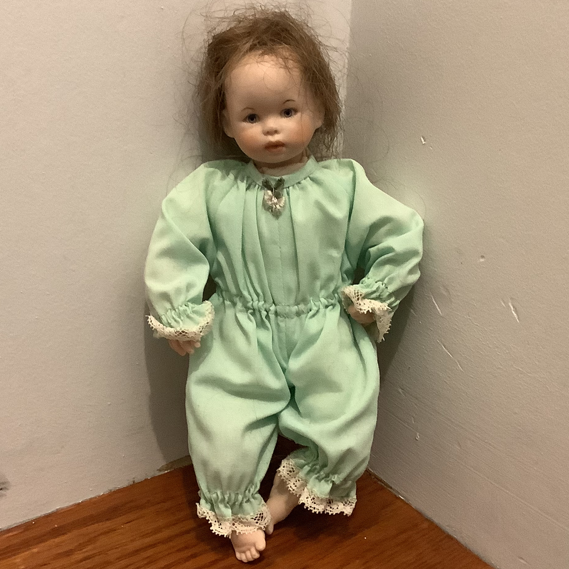 Modern 8 and a half inch baby doll with messy medium brown wig and green sleeper
