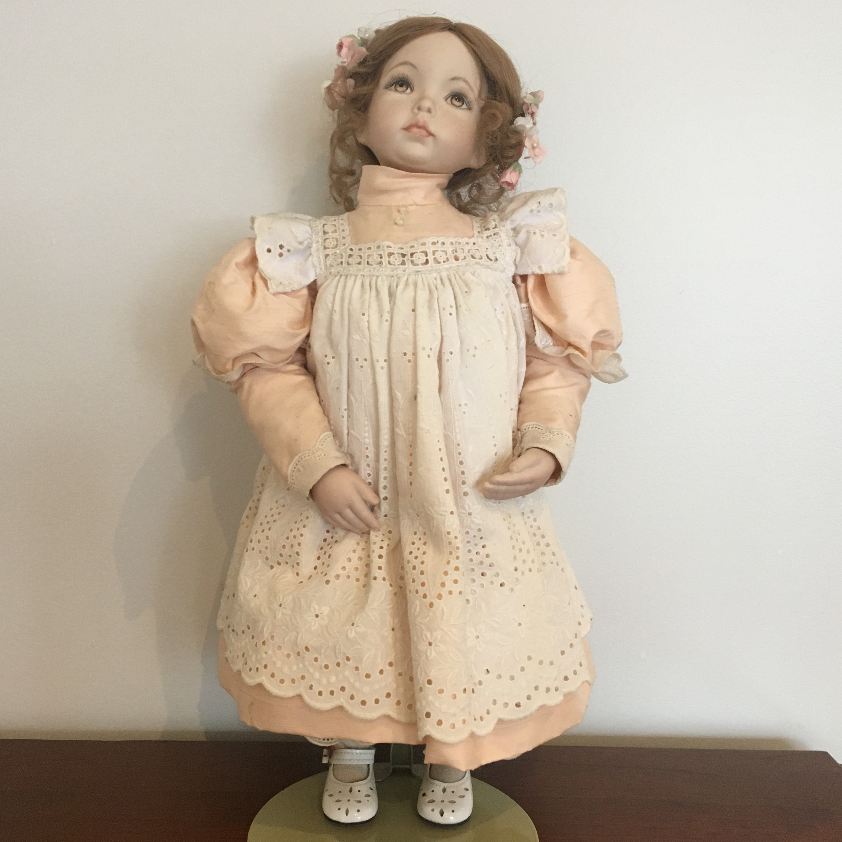 19-inch modern doll with brown hair in milkmaid braid with painted eyes and peach dress with white pinafore