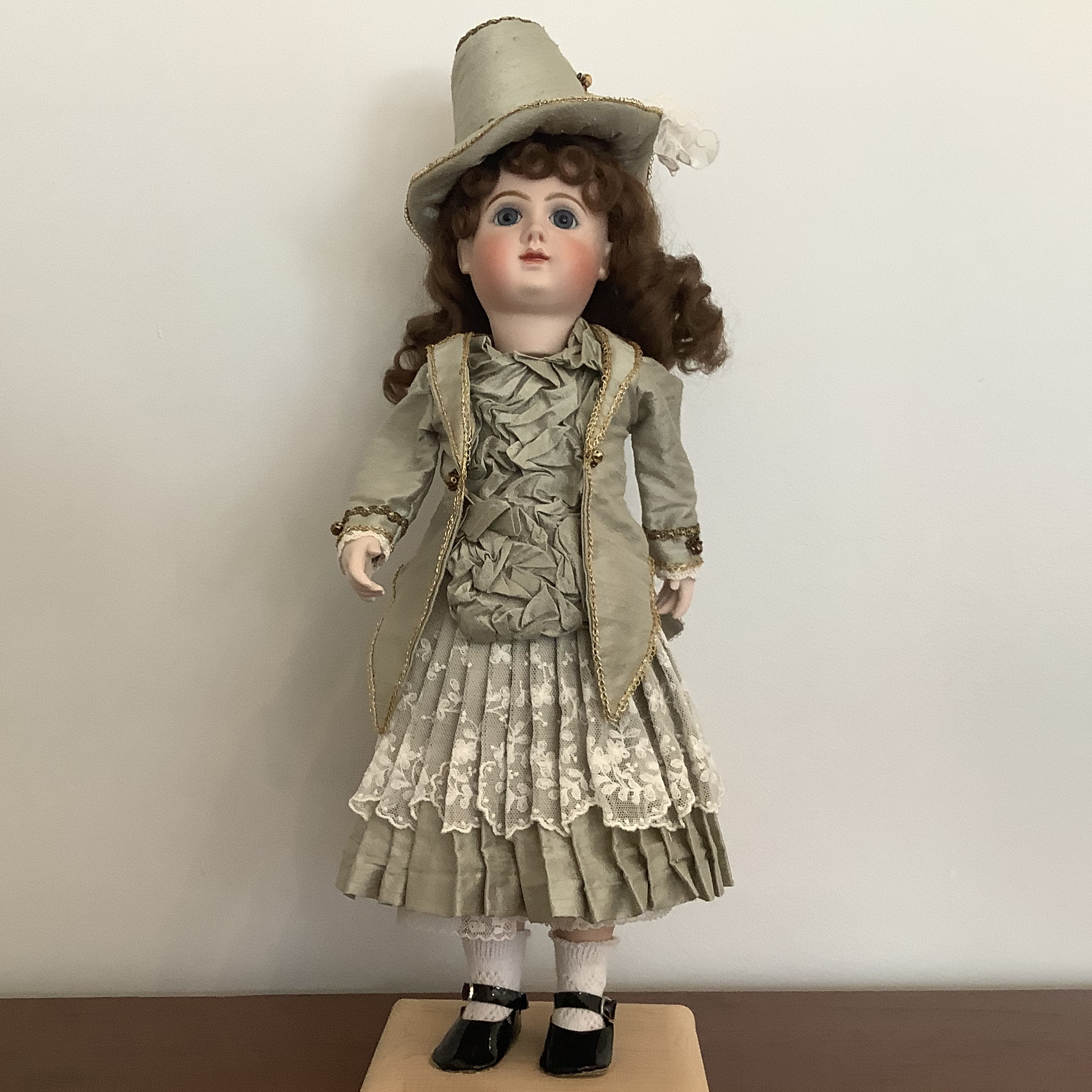 Reproduction mechanical Phenix Bébé doll in pale green suit with lace overlay and matching hat, front view