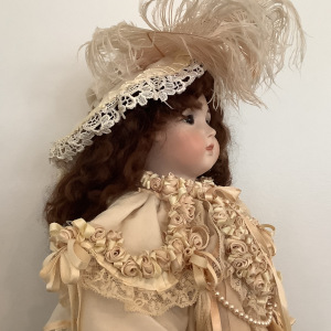 24-inch reproduction Cody Jumeau in elaborate off-white dress with ribbon roses and matching feathered hat, front view