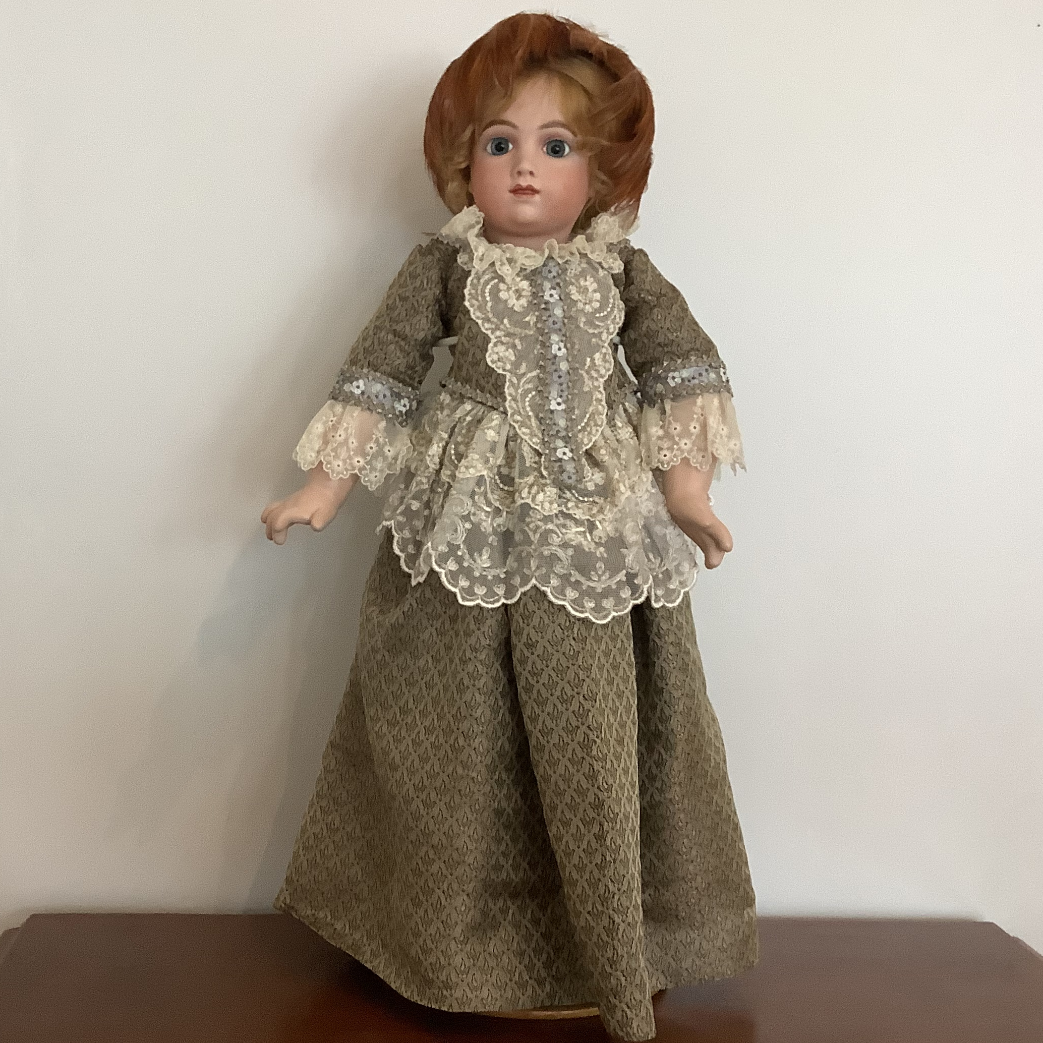 Reproduction AT doll in green and white silk dress with extensive lace trim and feathered fascinator hat, front view