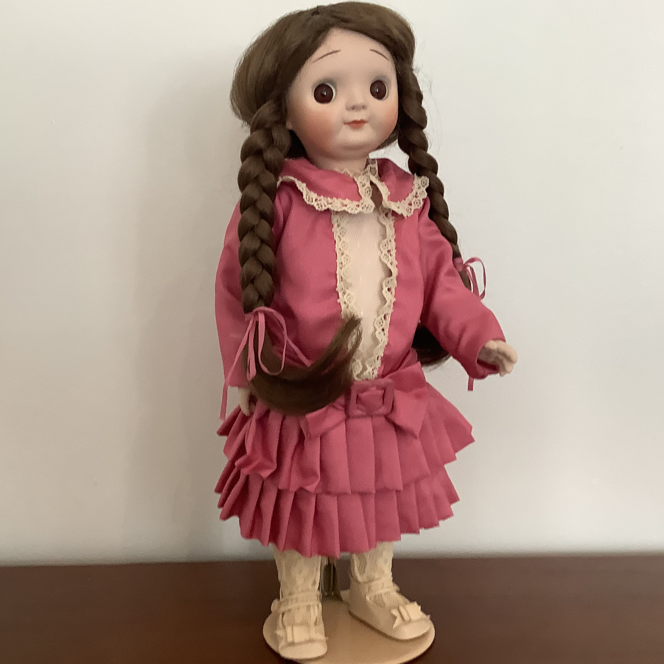 Reproduction Googly doll with braided pigtails and pink dress in modern materials, front view