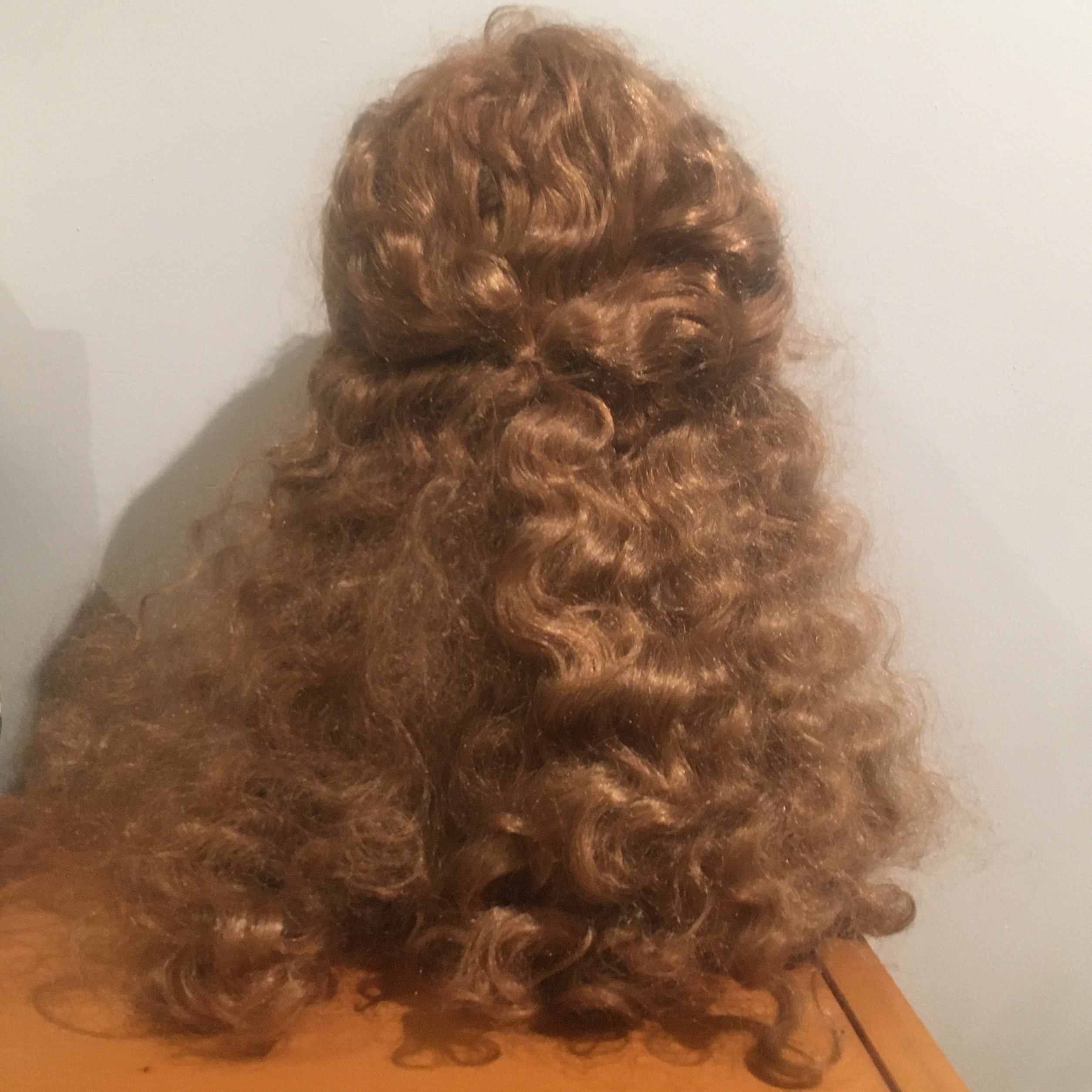 Very long, curly strawberry blond wig with short bangs and two front pieces tied together in the back