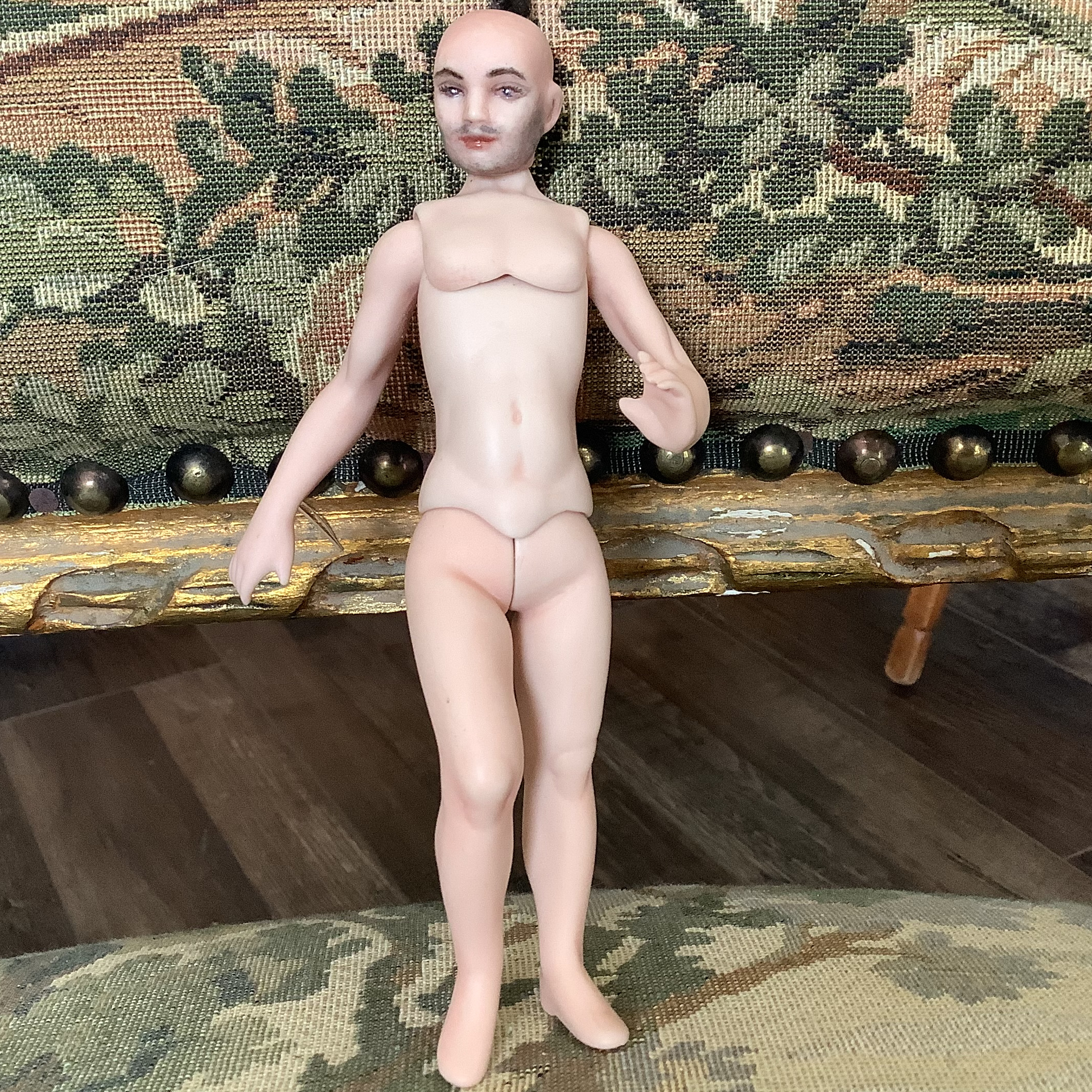 Nude male doll with painted five o'clock shadow and body stringing protruding from crown of head