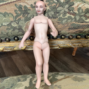Nude male doll with painted five o'clock shadow and body stringing protruding from crown of head