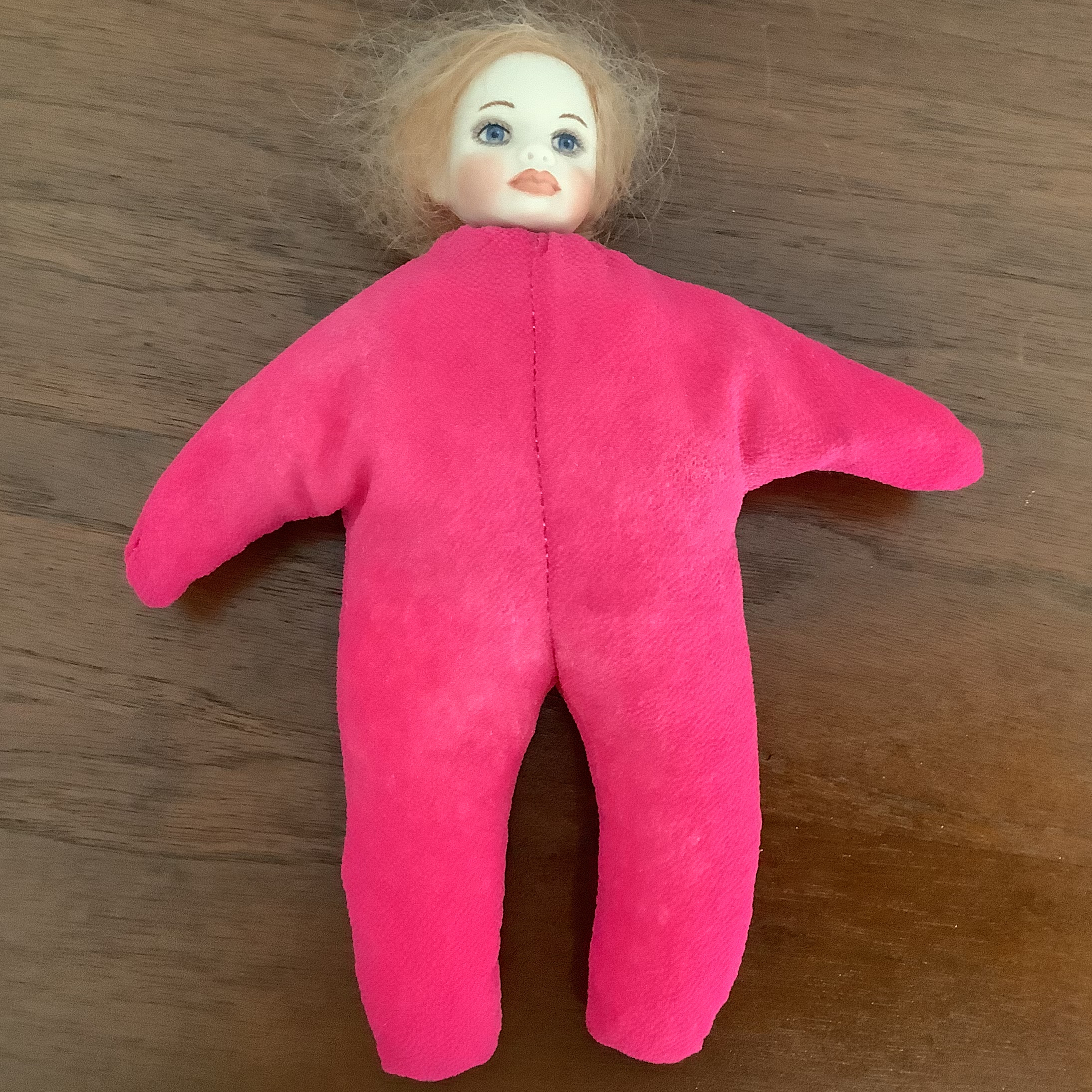 Heavily made-up baby doll with very light skin with a shocking pink starfish body