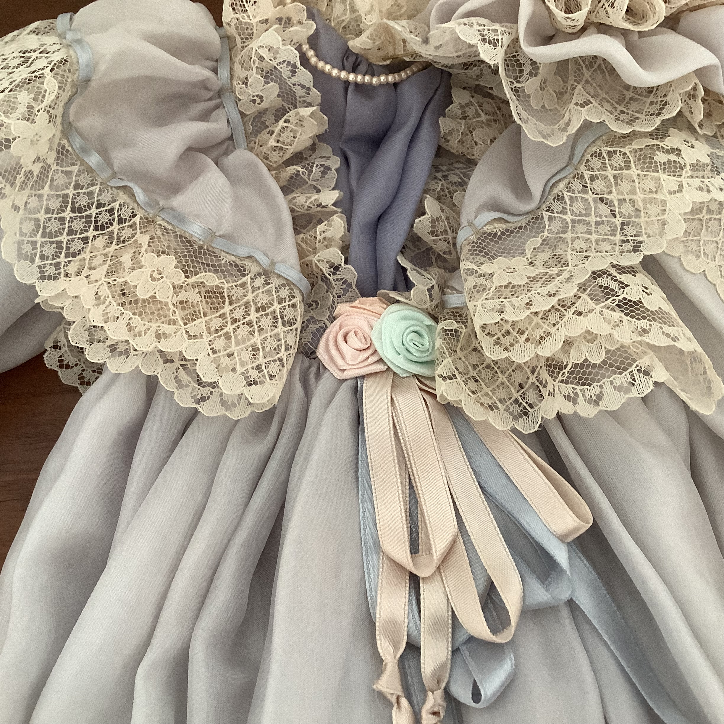 Close-up picture of grey lace-trimmed dress with ribbon rose overlay removed