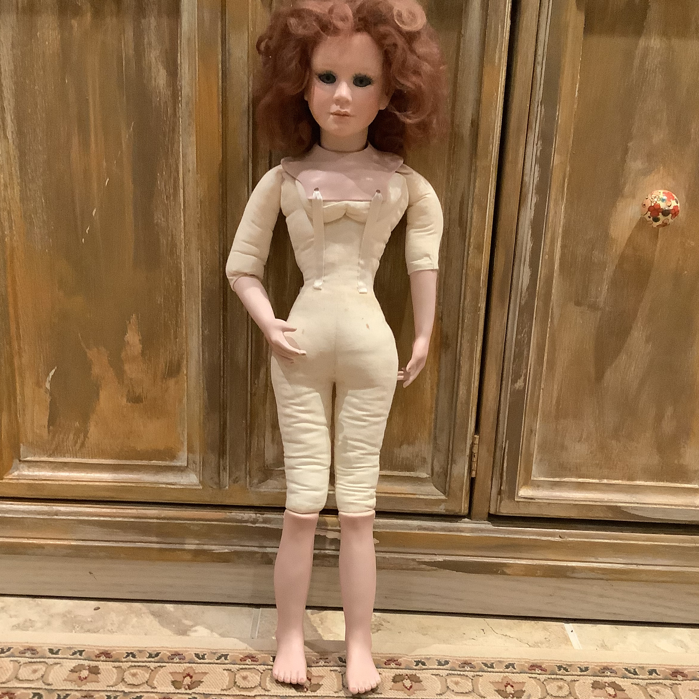 Nude lady doll with fabric body and unstyled red hair, and fully painted face