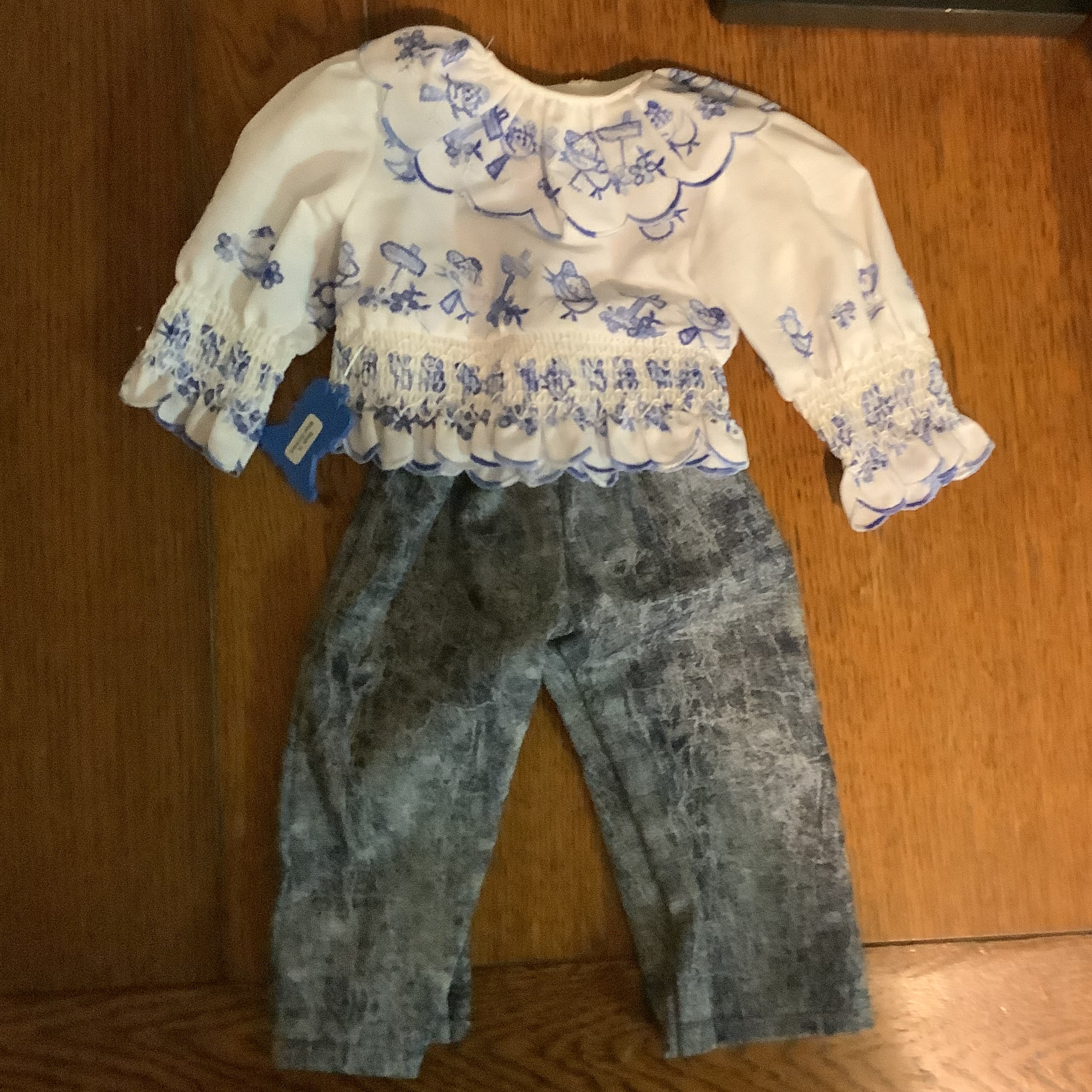 blue jeans and white smocked cotton shirt printed with small birds and play scenes