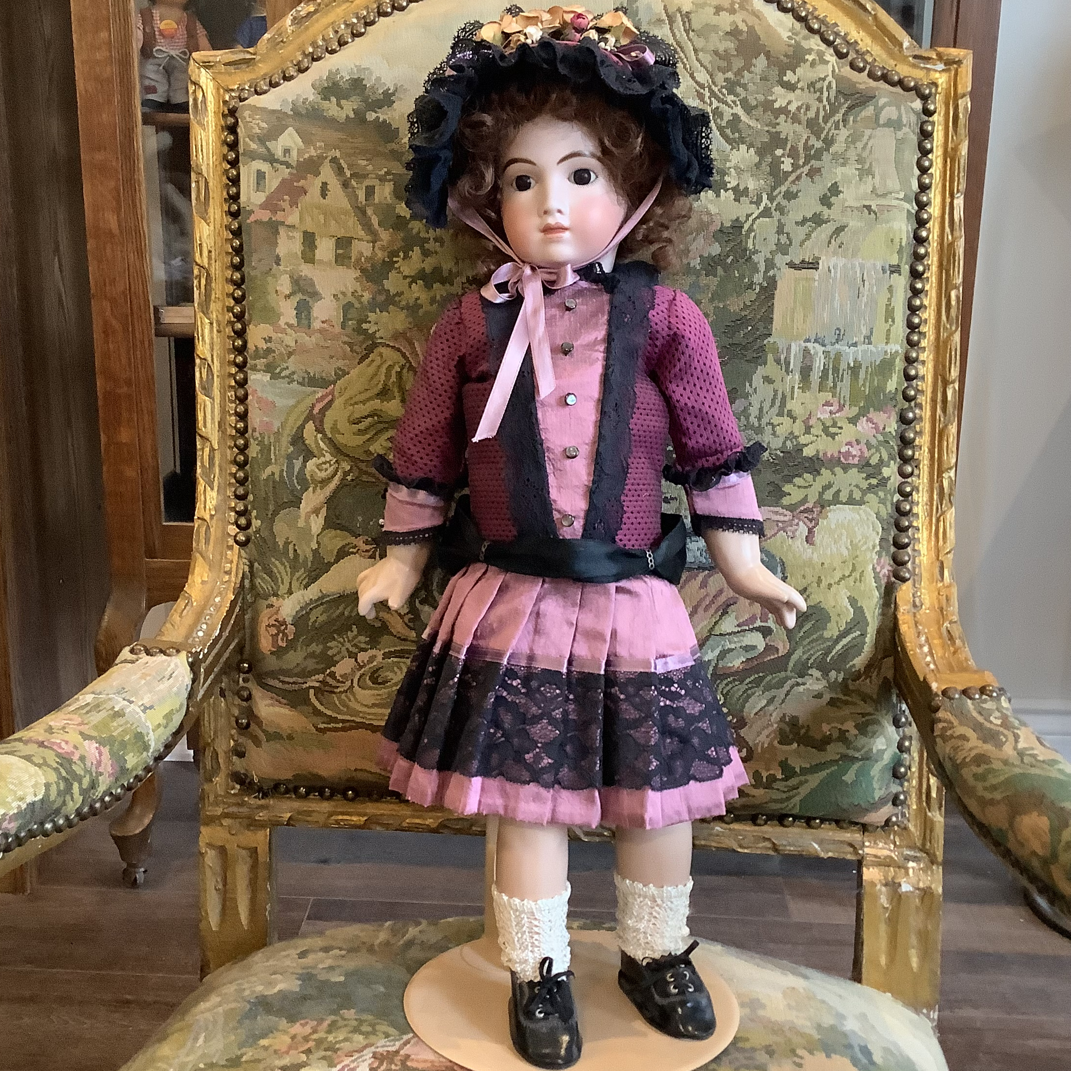 23 inch reproduction of AT 11 doll with light skin, curly brown shoulder-length hair, and pink and black suit