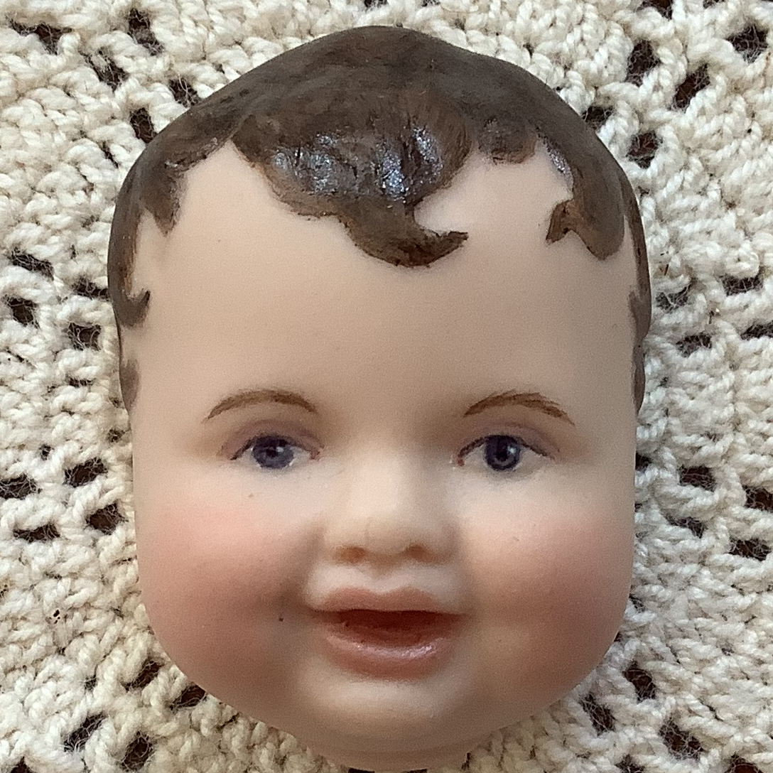 Brooch of a short-haired baby's face with light skin and dark brown hair