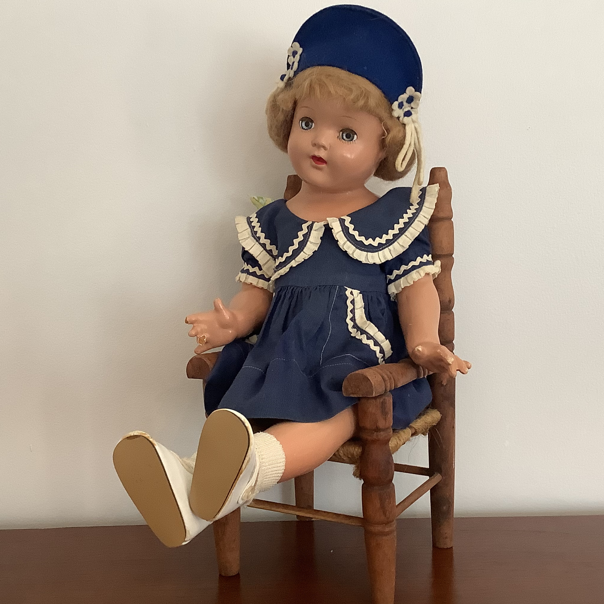 Sailor girl doll in blue minidress sitting in a miniature chair