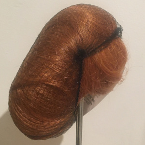 Dark red wig with medium short straight hair contained within a hair net