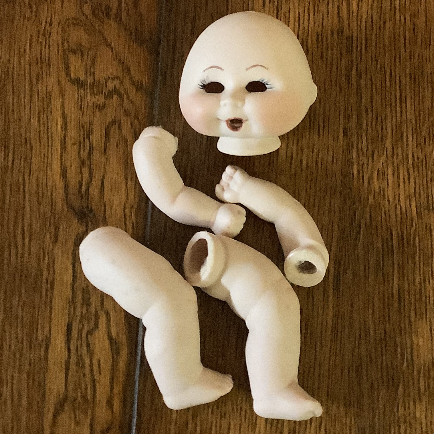 Doll parts including a light-skinned smiling head without eyes, arms, and legs