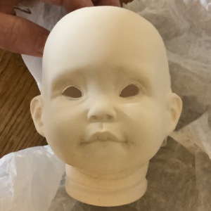 Unfired, unglazed porcelain head depicting a child's face in unpainted white ceramic