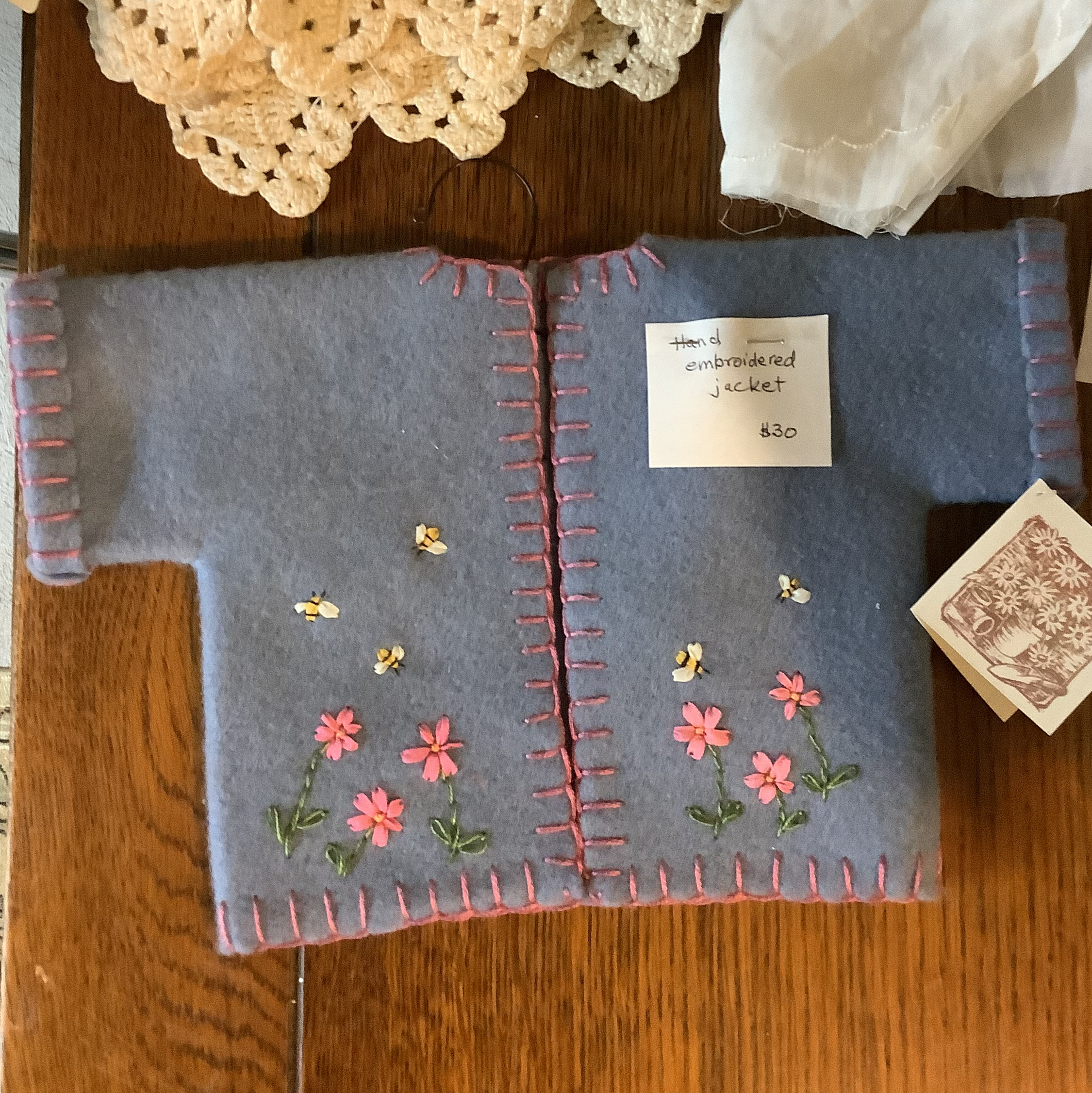 blue felt jacket with pink blanket-stitched edges and embroidered bees and flowers