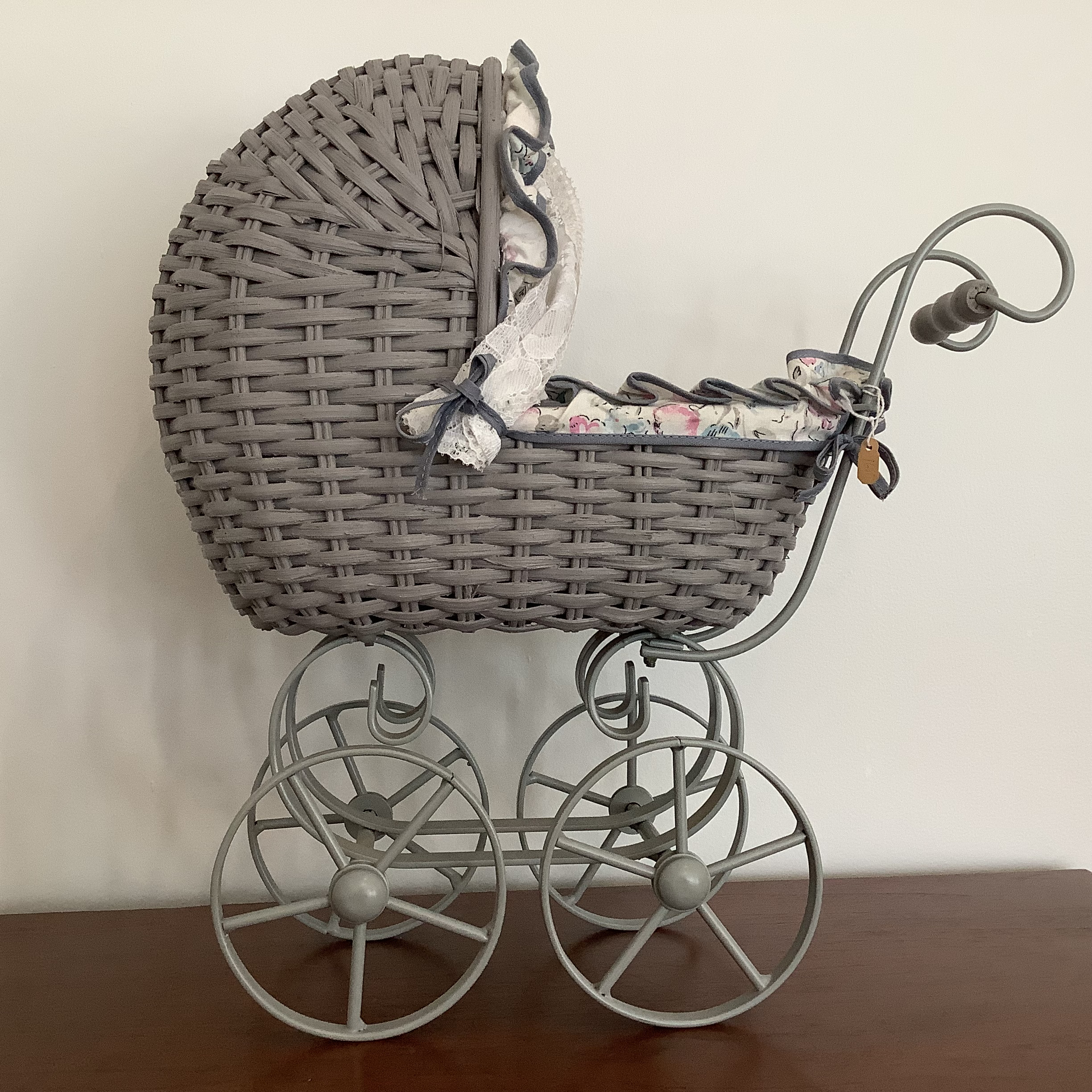 Grey-painted wicker stroller with extensive padded lining and curtains in a floral print