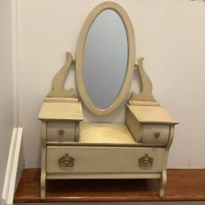 Small, beige-painted wooden vanity with mirror and three drawers, front view