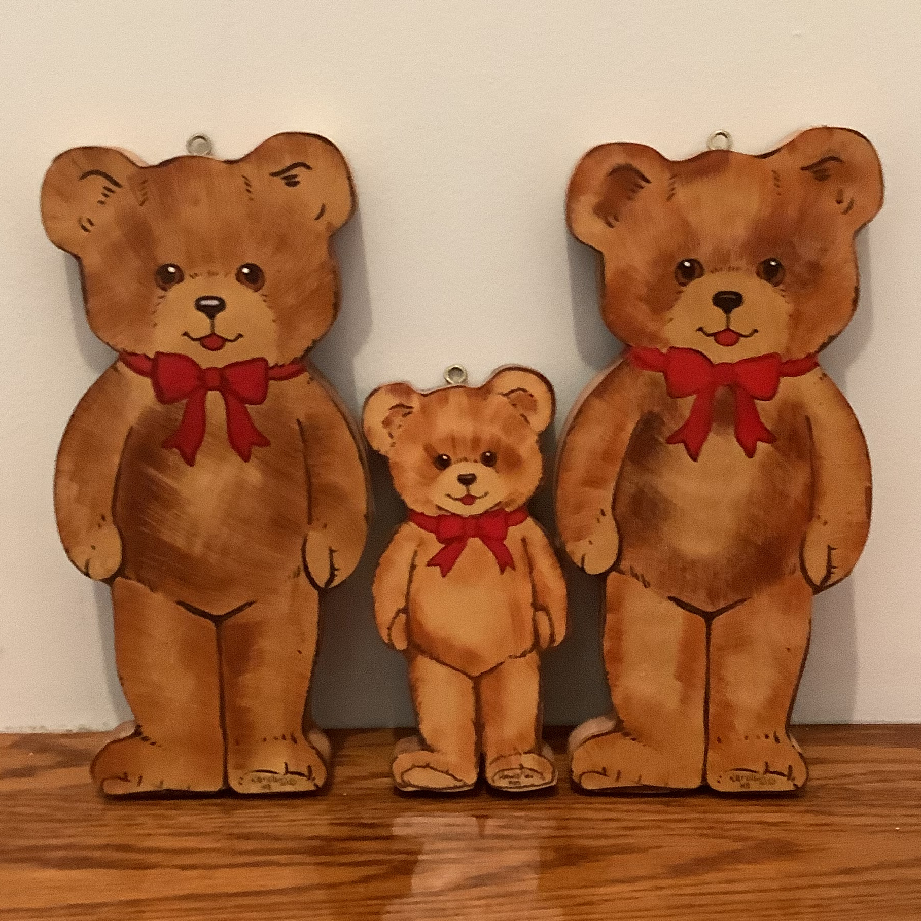 Flat wooden bear ornaments painted to look like realistic teddy bears, two large and one small