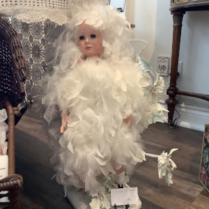 Larger fairy doll wearing dress made entirely from white feathers