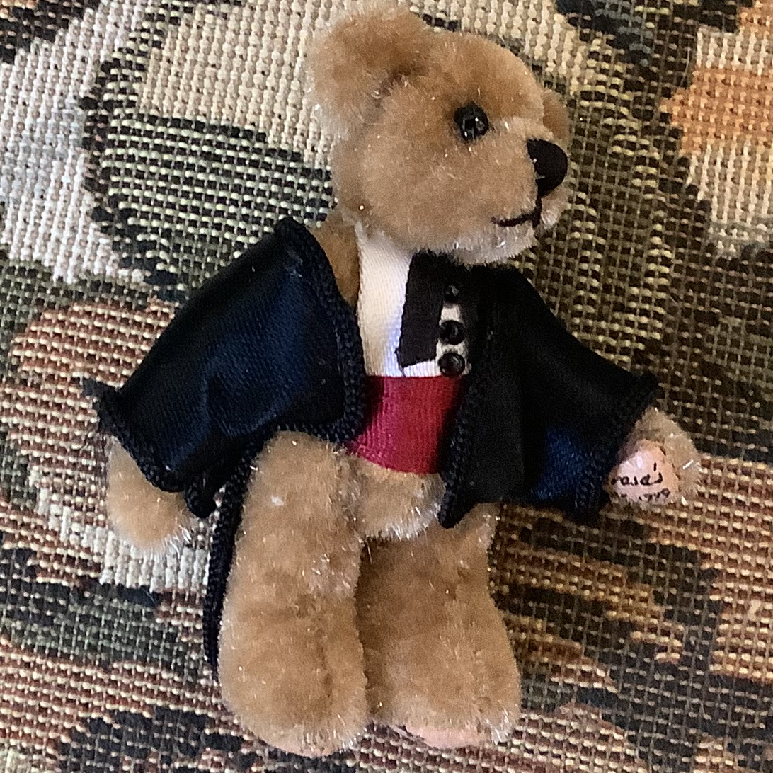Small teddy bear doll in suit jacket and tie with jointed arms and legs