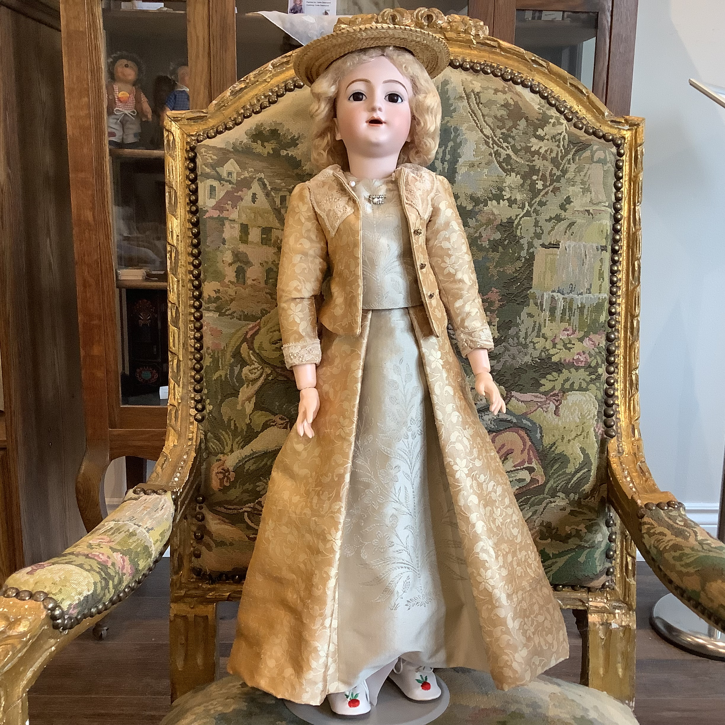 Small, white-haired doll in Tudor hat and short brown dress with lace cuffs.