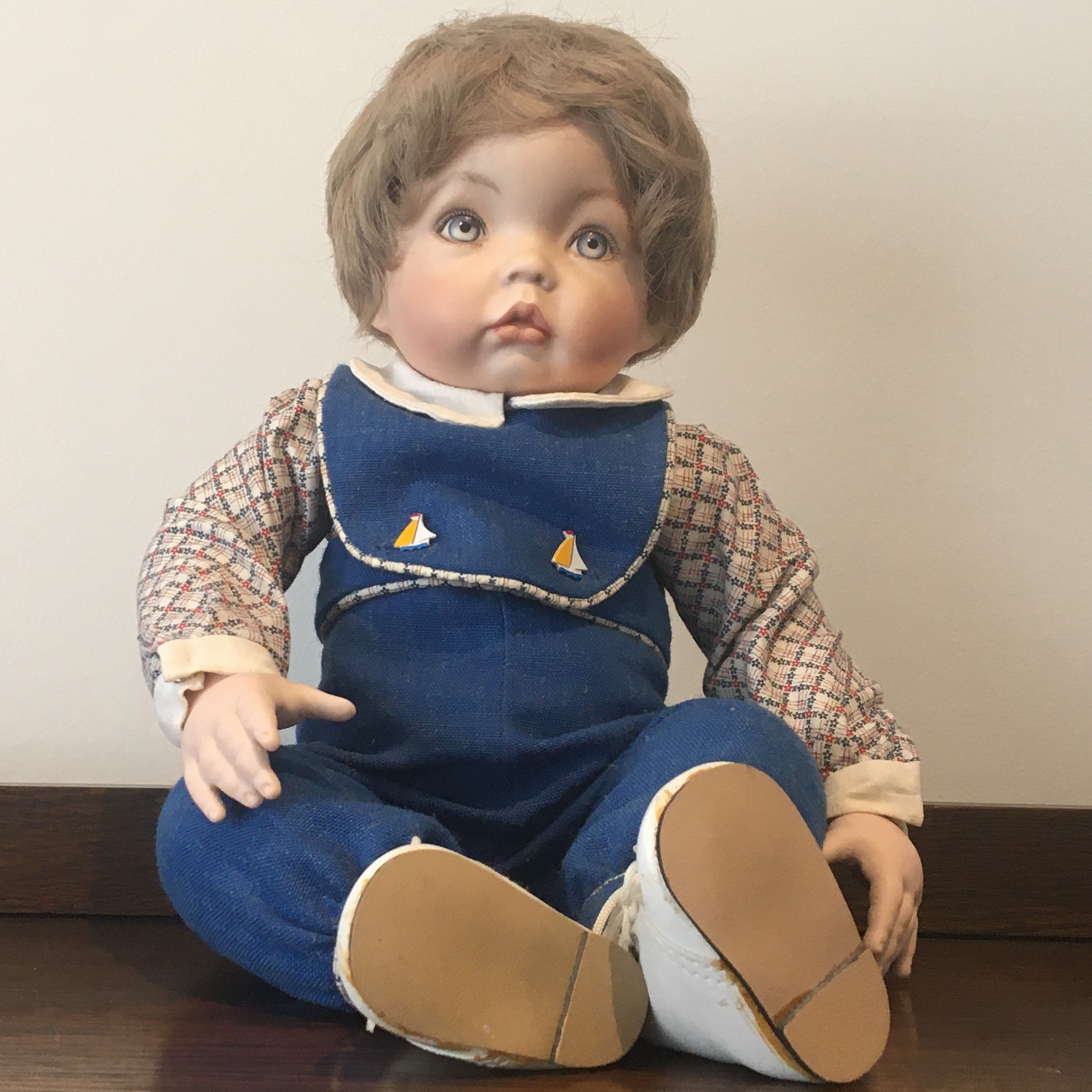 seated 17-inch Modern doll Aaron with ash blond wig and blue overalls