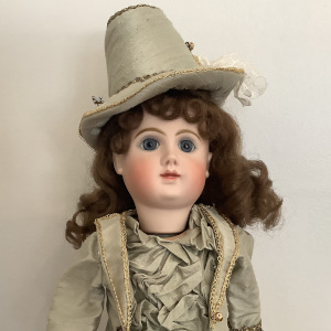 Reproduction mechanical Phoenix Bébé doll in pale green suit with lace overlay and matching hat, front view