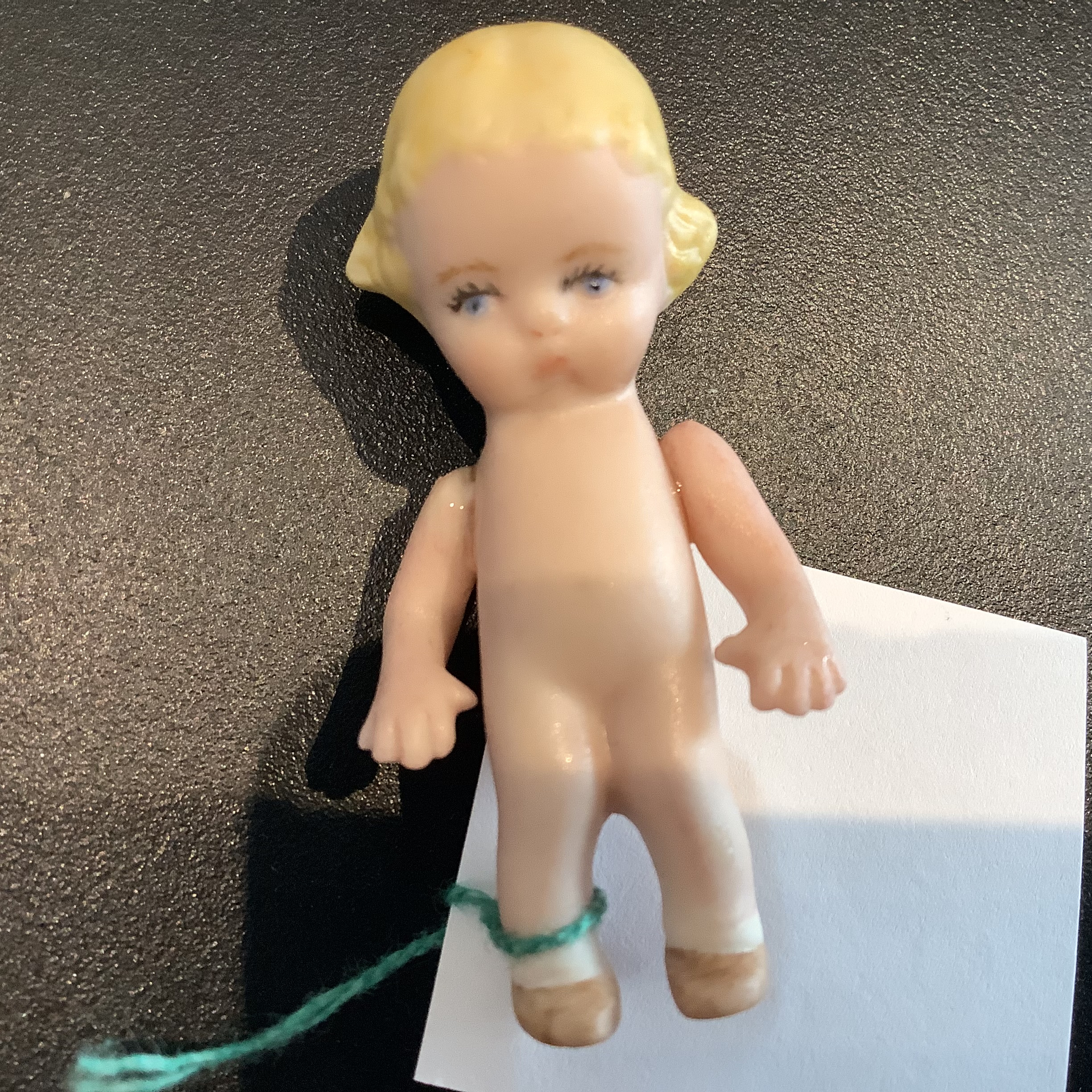 Very small porelain Kewpie doll with molded hair and legs and glued-on arms